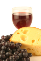 Grapes and cheese on a background of a glass with red wine.