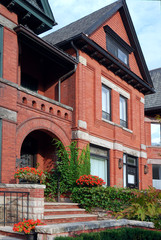 Fototapeta na wymiar Wiktoriański dom z czerwonej cegły i łukowatym wejściem bluszczu