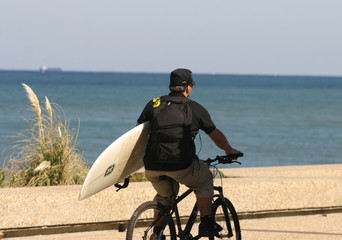 homme à vélo avec une planche de surf