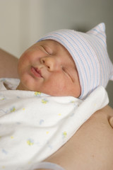 Newborn baby boy on mothers arm close-up on child face