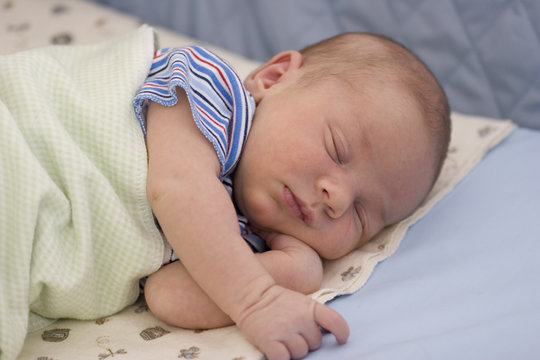 Newborn baby boy sleeping in bed