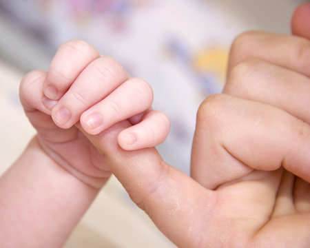 Baby'sl ittle hand on mothers finger, Child holding parent hand, newborn baby boy