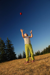 girl throwing red apple in air