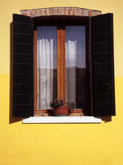 Green shutters on yellow house in Burano, Venice, Italy