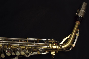 Saxophone against black, mouthpiece, neck and top keys