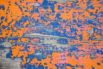 A plank of wood with peeling orange and blue paint.