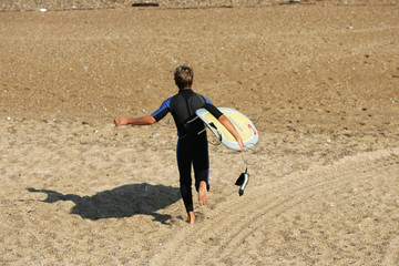 gar&ccedil;on entrain de courir pour aller faire du surf