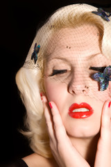 Blonde woman with hair net holding her face and looking down.