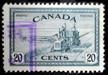 Wheat harvest and 1930s style combine on old Canada stamp