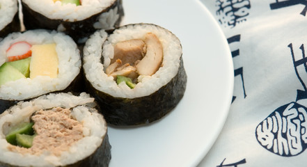 left aligned sushi rolls on plate with kimono background