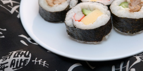 sushi rolls on plate with black kimono background