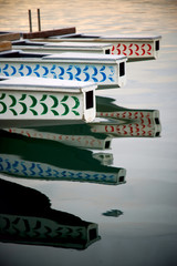 The helm of four dragon boats reflecting on the ocean surface