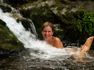 laughing girl bathing in the forest waterfall