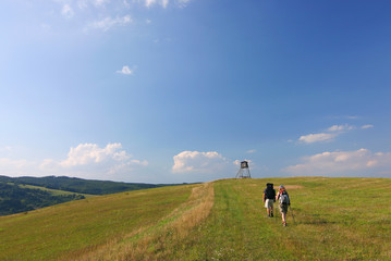 hikers on the meadow under blue sky