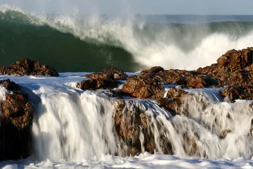 Papier Peint photo Lavable Eau Large ocean waves crashing over rocks at the sea side