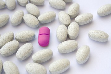 Fototapeta na wymiar Różowe tabletki pigułka wśród szarych