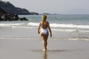 Fototapeta premium femme en maillot de bain qui marche sur la plage