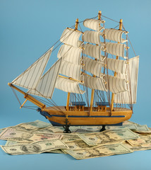 Sailing vessel on waves from dollars on a blue background.