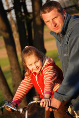 A father and daugther riding a bike outside