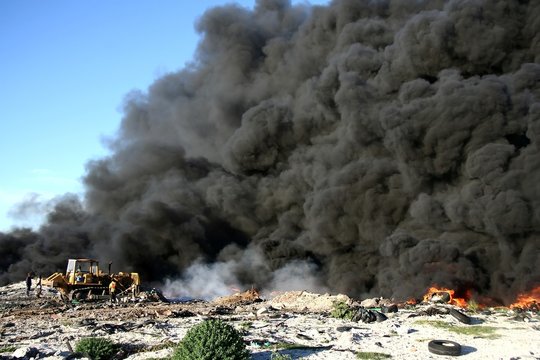 Bulldozer taming out of control fire of tyres at a tip site 