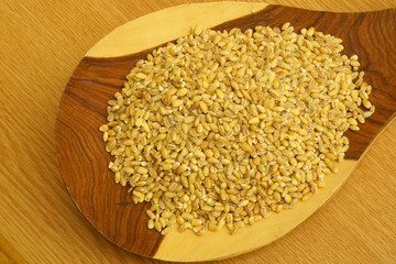 Pearl barley on the big wooden spoon