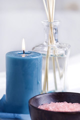 Bath salts and candle set against white bath tub area