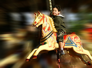 Fototapeta na wymiar Young boy thrilled on the carousel ride, 