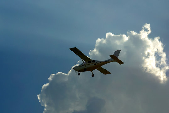  Silhouette Of A Small Plane  With The Clouds