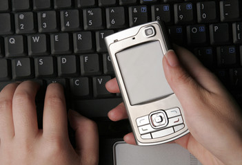 Hands And Mobile Phone On Laptop