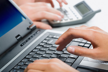 Hands typing on a laptop