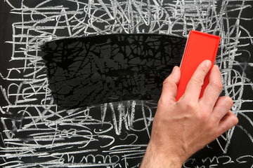 Cleaning a blackboard with a red chalk duster. © Sharpshot