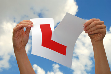 Woman holding ripped L plate after passing driving test