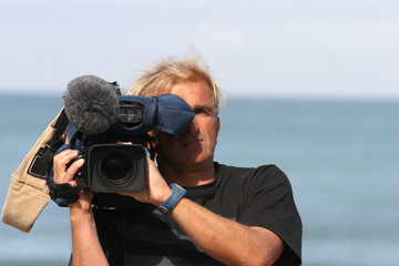 homme entrain de filmer avec une caméra professionnelle - obrazy, fototapety, plakaty