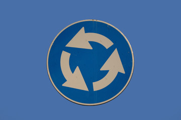Roundabout sign isolated on blue