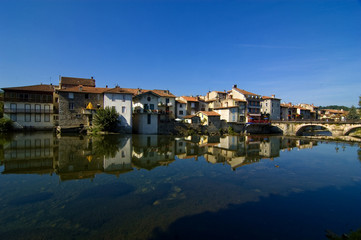 Fototapeta na wymiar French village against blue sky and reflected in river
