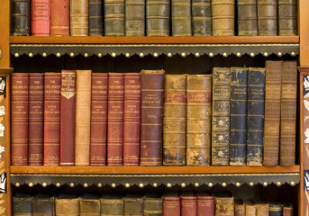 Lots of old books on a bookshelf in library. - obrazy, fototapety, plakaty