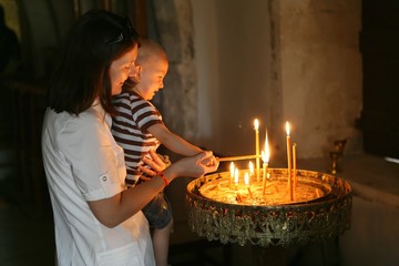 Mom and kid lighting candles in a church
