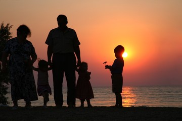 Fototapeta na wymiar Seniorzy i dzieci na zachodzie słońca