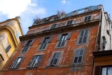 dilapidated front of red building with bars at the windows 