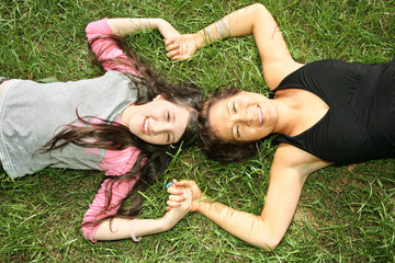 girl and woman on grass holds by hands