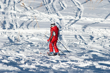 Woman in red and ski traces on snow