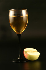  Glass of white wine and an apple on a black background