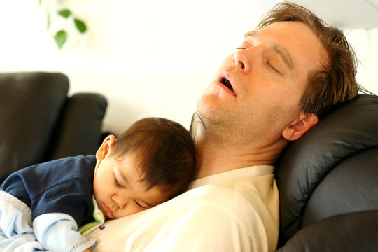 Father Sleeping On Chair With His Baby Boy On Chest