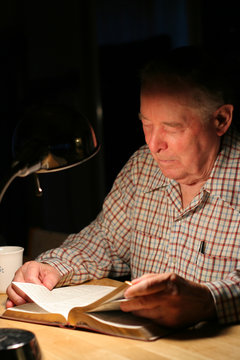 Elderly Man Reading His Bible Under The Lamp Light 