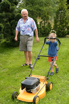 Grandfather And Grandson Mowing Grass