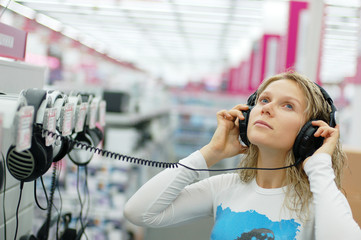 girl listening music with headphones in store