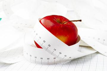Red apple and measuring tape. Symbolic.