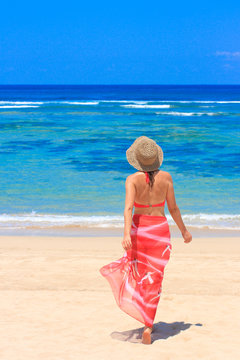 Girl in pareo walking towards the sea