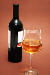 Glass of wine and a bottle on biege  background