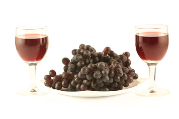 Two glasses of red wine and grapes isolated on white .